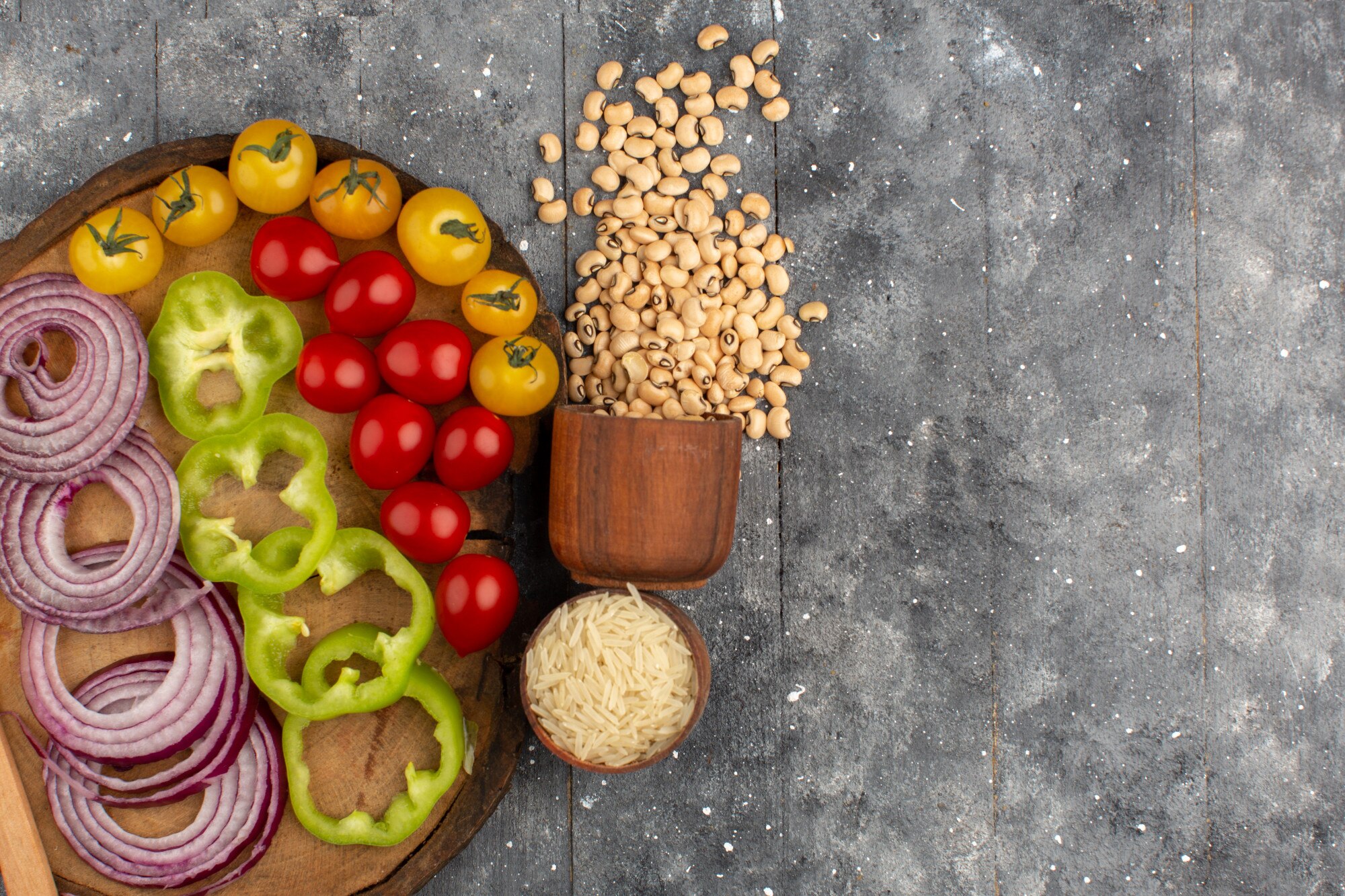 Tazón de alimentos frescos y coloridos: vegetales, legumbres y granos sobre mesa de madera